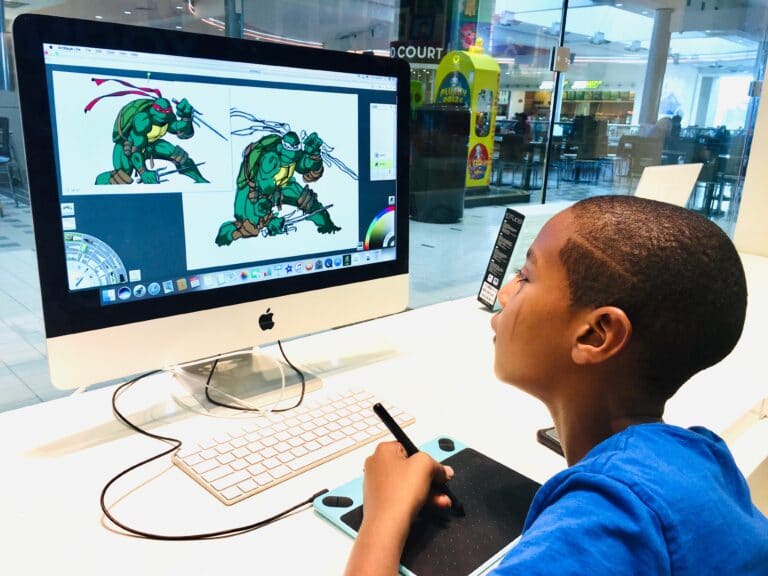 art student on iMac computer drawing a cartoon character in green