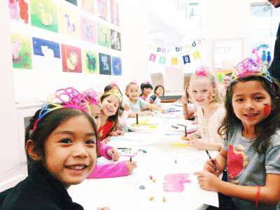 Group of girls gather around a table for a birthday party