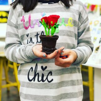 student holding flower plant clay