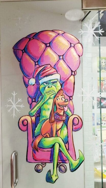 image of the grinch sitting in a red chair drawn on glass