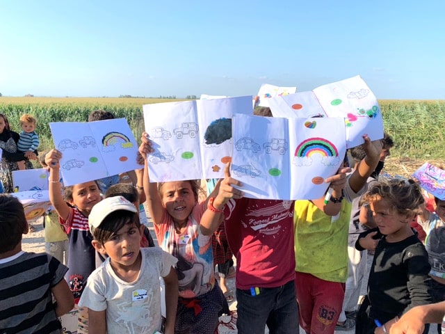 image of a group of students outside holding art above their heads