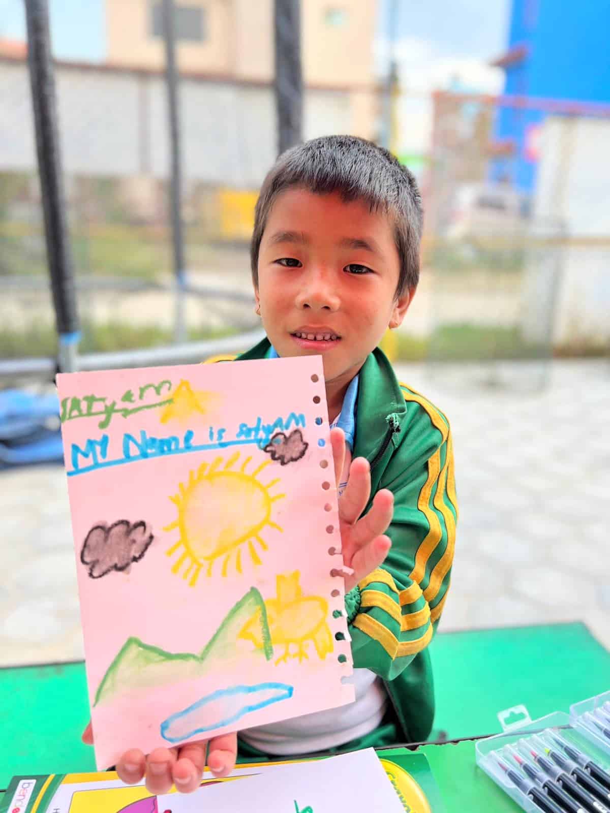 image of a boy holding his art in front of him