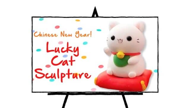 white cat sculpture with red collar and green stomach with gold name tag, lucky cat sculpture