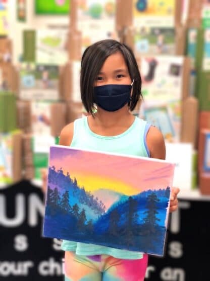 student holding painting of mountains