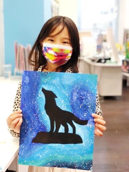 student holding painting of a wolf