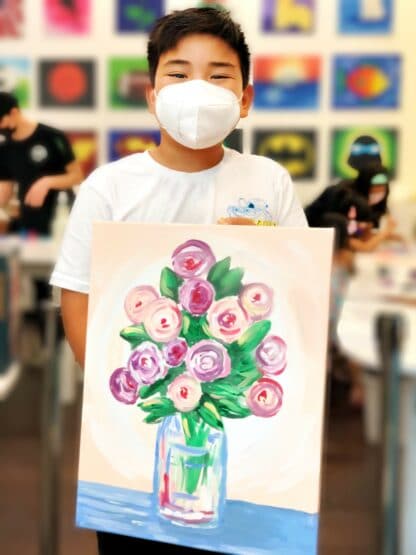 student holding painting of vase of flowers