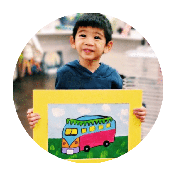 young boy holding drawing of colorful bus