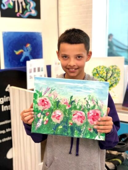 image of student holding artwork with field and flowers