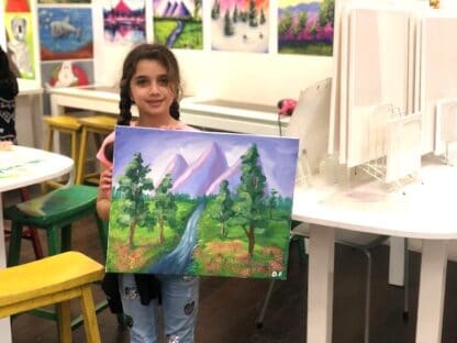 image of student holding artwork with purple background mountains and green trees