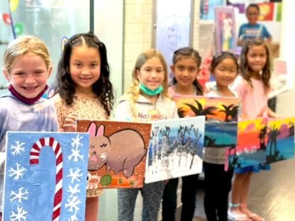 image of girls holding winter themed paintings on canvas