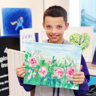 boy holding canvas painting of pink flowers with green and blue background