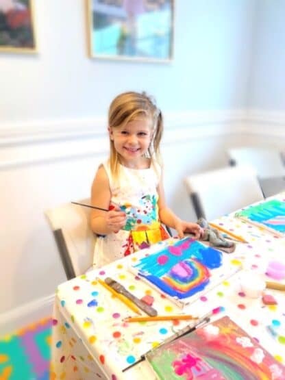 image of birthday guest smiling and paiinting a rainbow