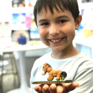 a boy holding a horse clay sculpture