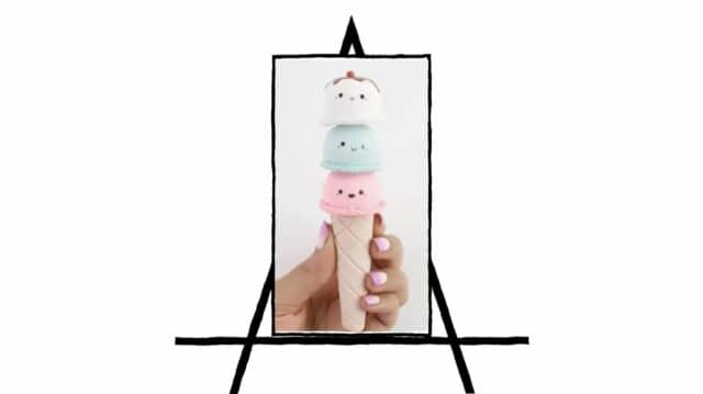 image of hand holding an ice cream cone with 3 scoops of ice cream with faces