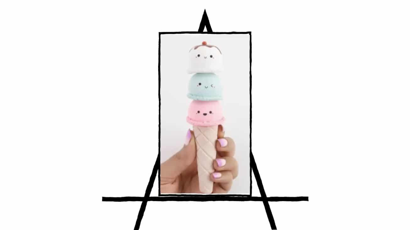 image of hand holding an ice cream cone with 3 scoops of ice cream with faces
