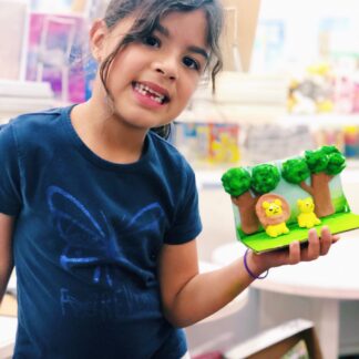 girl holding a clay scene of lion and trees