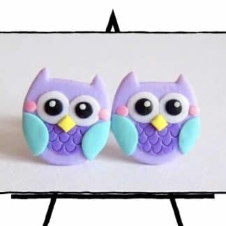 image of two clay owls with purple bodies and teal wings, yellow nose, big eyes