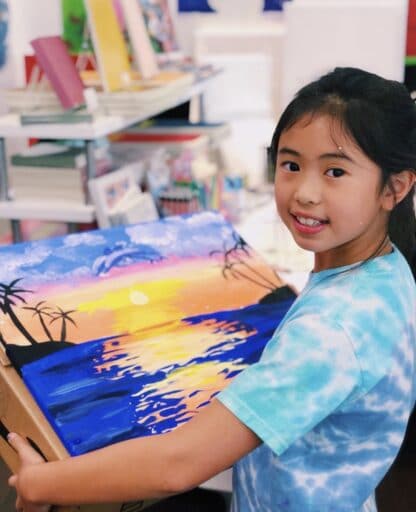 image of student holding sunset artwork