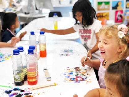 image of kids laughing with science projects on white tables