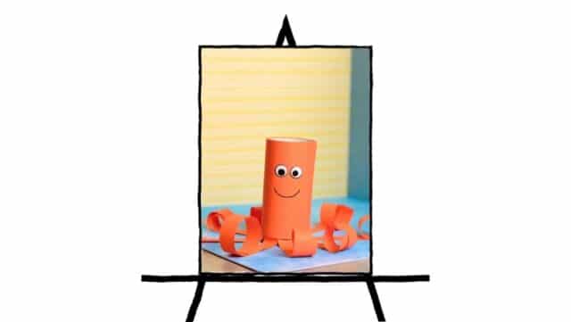 image of orange paper tube with smiling face and rolled paper on sides to look like an octopus
