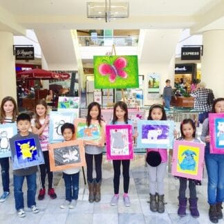 group of birthday guests holding their artwork
