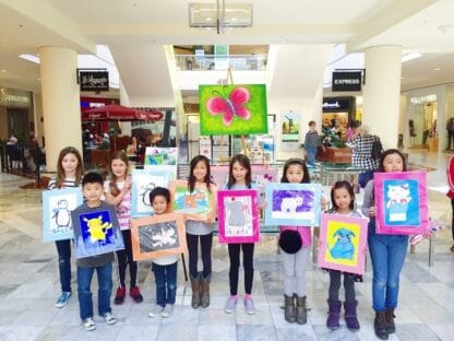 group of birthday guests holding their artwork
