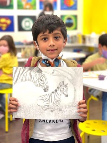 boy holding pencil sketch of zebras