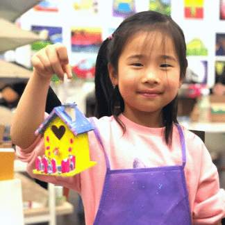 Smiling student with her Bird house craft