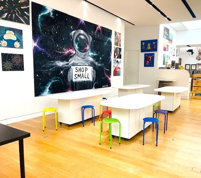 iimage of tables and chairs inside studio with paintings on the wall