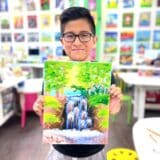image of a young boy holding up his canvas painting of a waterfall scene