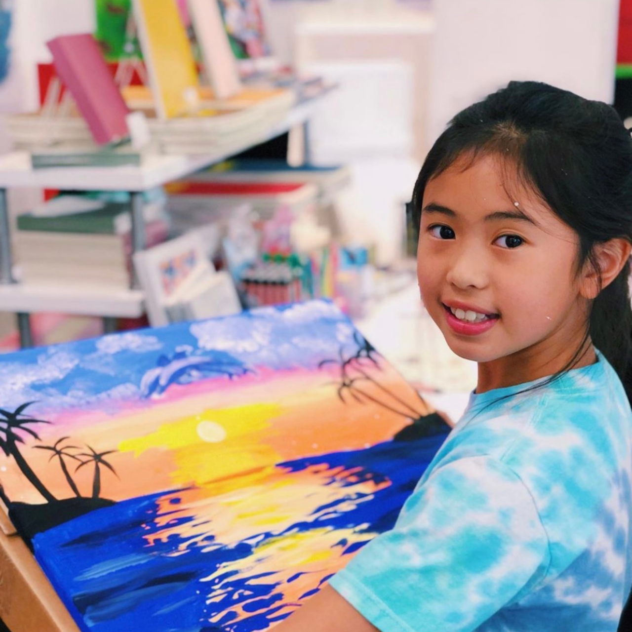 image of a young girl holding a painting of a sunset on a canvas