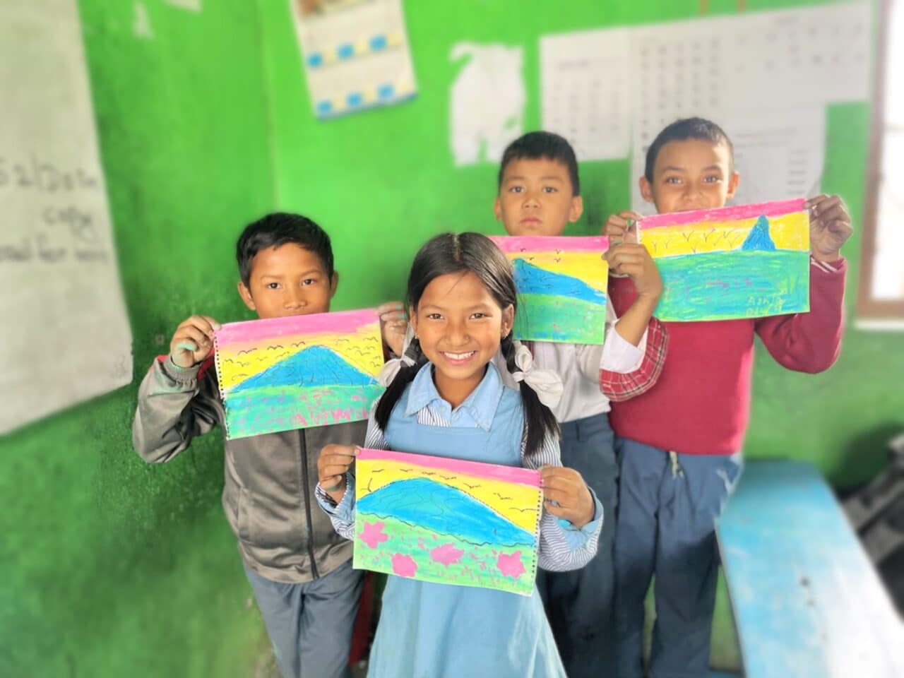 image of 4 kids standing in front of a green wall holding paintings of colorful fields in front of them