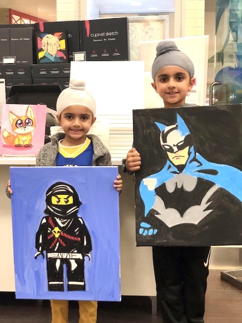 image of 2 boys holding canvases with batman and lego art on them