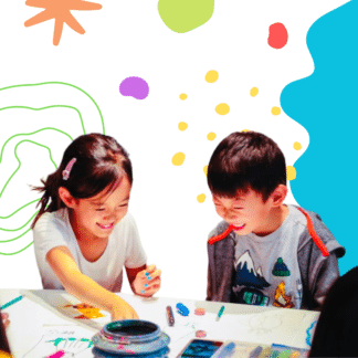 image of two young kids smiling as they work on their art projects