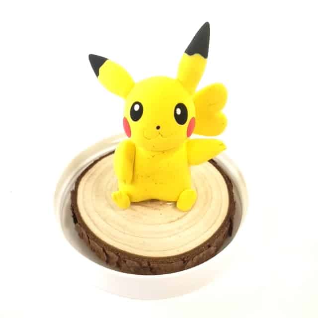 image of a clay Pikachu sculpture sitting on a round of wood